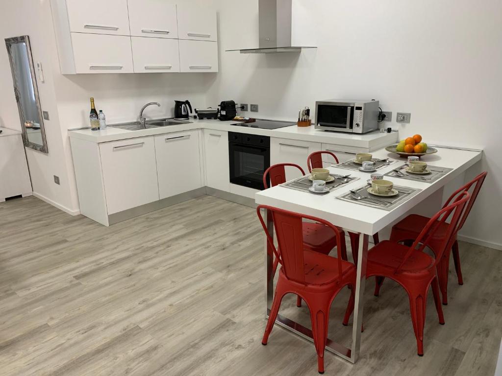 a kitchen with a white table and red chairs at Appartamento La Bottega in Piove di Sacco