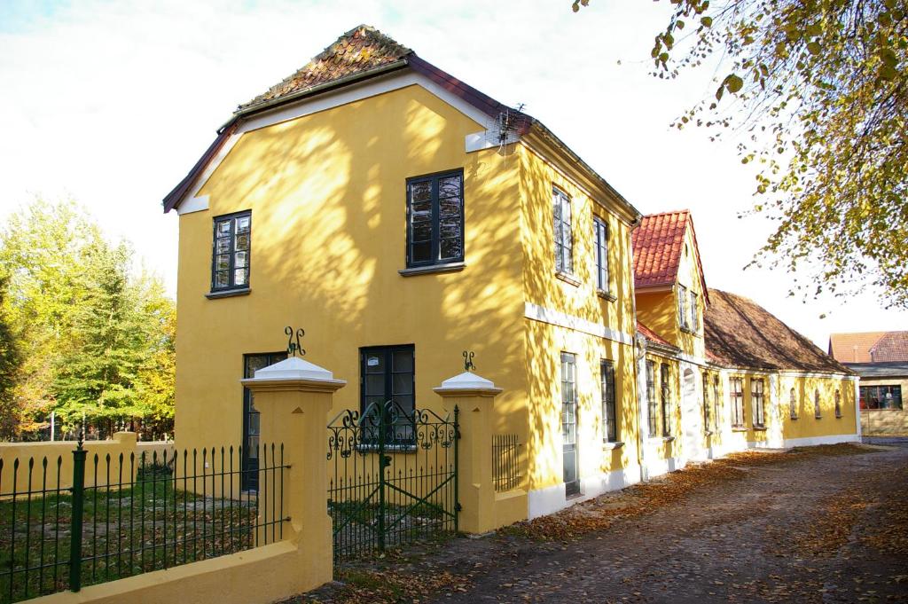 una casa gialla con una recinzione di fronte di Villa Nikolaj - Historisches Pastorat a Fehmarn