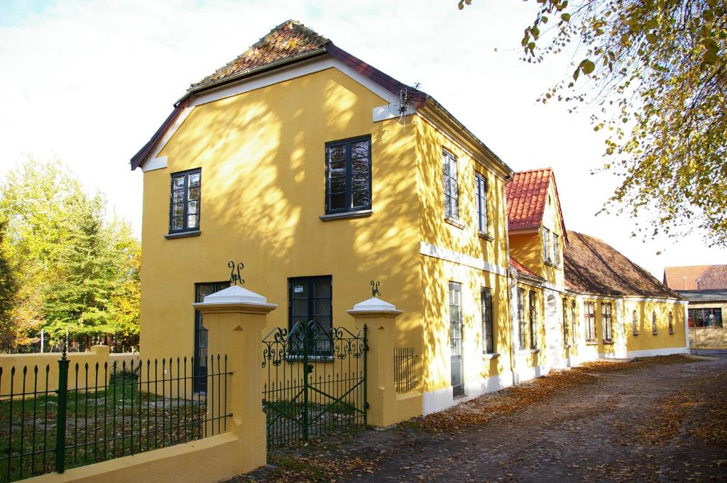 a yellow house with a fence in front of it at Villa Nikolaj - Historisches Pastorat in Fehmarn