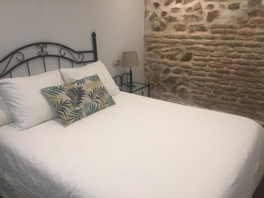 a bedroom with a white bed and a brick wall at Apartamento Tolaitola in Toledo