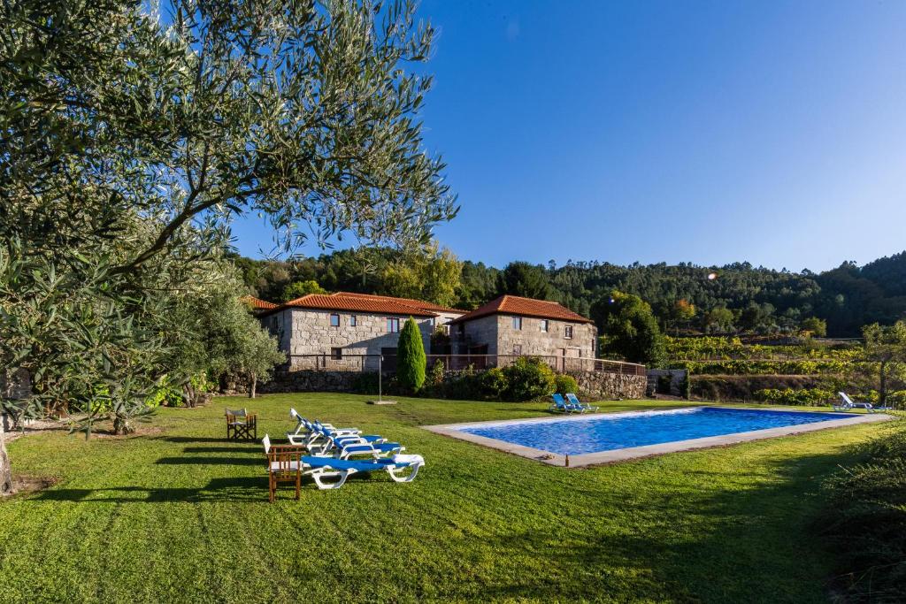 a yard with a pool with chairs and a house at Quinta da Pousadela - Agroturismo in Amarante