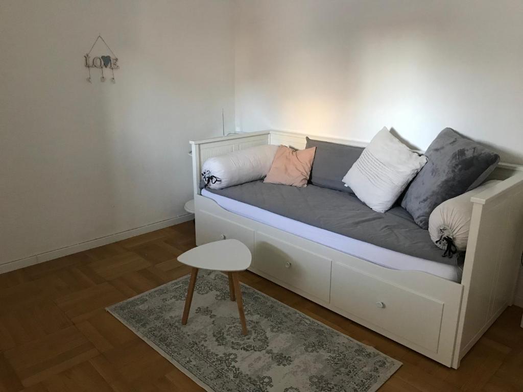 un divano bianco con cuscini e uno sgabello in una stanza di Small Home a Freudenstadt