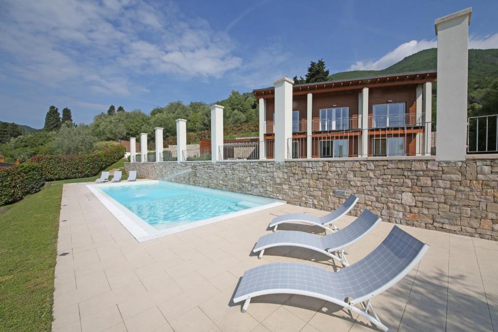 a house with a swimming pool and two lounge chairs at Villa Albachiara, Private Luxury villa with private pool and lake view in Gardone Riviera