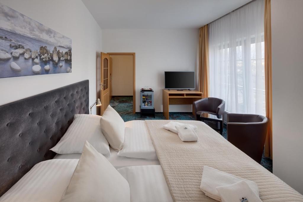 プラハにあるホテル オヤの大きなベッドとデスクが備わるホテルルームです。