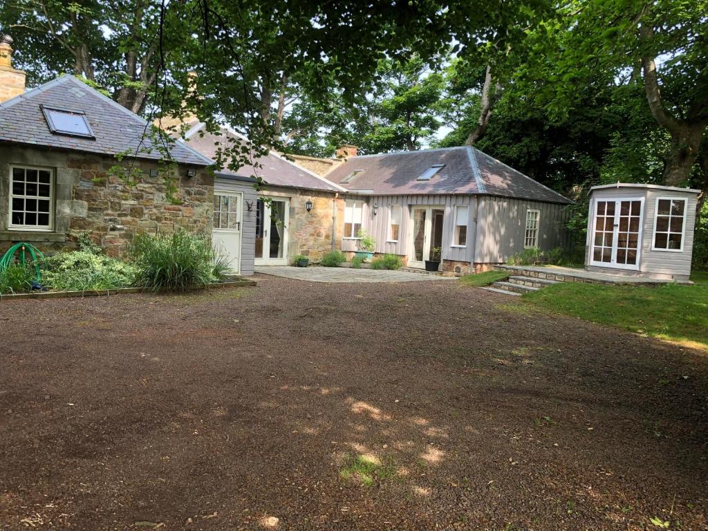 an old stone house with a driveway in front of it at Luffness Castle Cottage in Aberlady