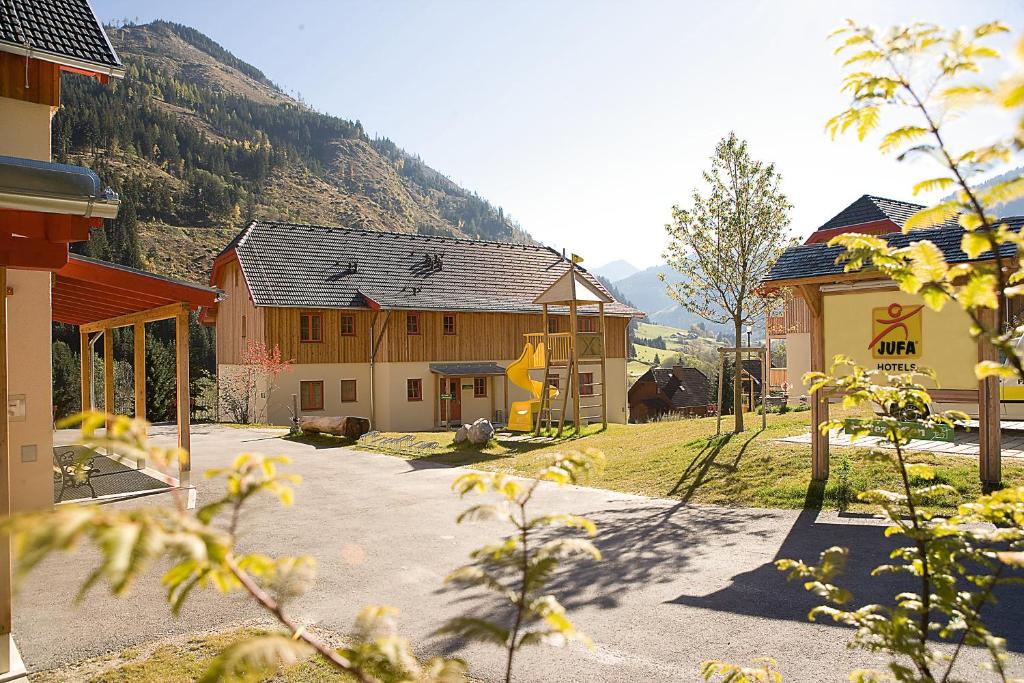 un groupe de bâtiments avec des montagnes en arrière-plan dans l'établissement JUFA Hotel Donnersbachwald, à Donnersbachwald