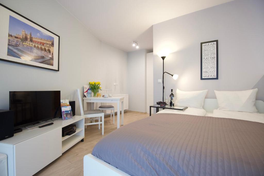 een witte slaapkamer met een bed en een televisie bij Kraków Apartments - Solna Studio & Apartments in Krakau
