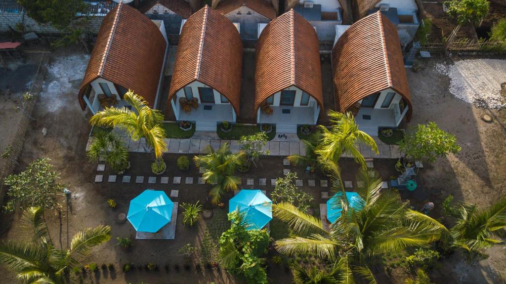 an aerial view of a resort with palm trees and blue umbrellas at The Rurus Bungalow in Nusa Penida