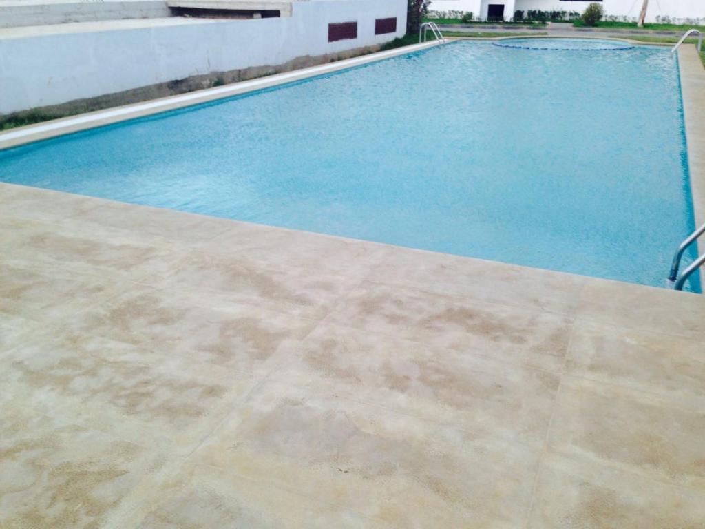 een zwembad met blauw water in een gebouw bij Achakar Hills , Piscine , Vue & Accès à la mer in Tanger