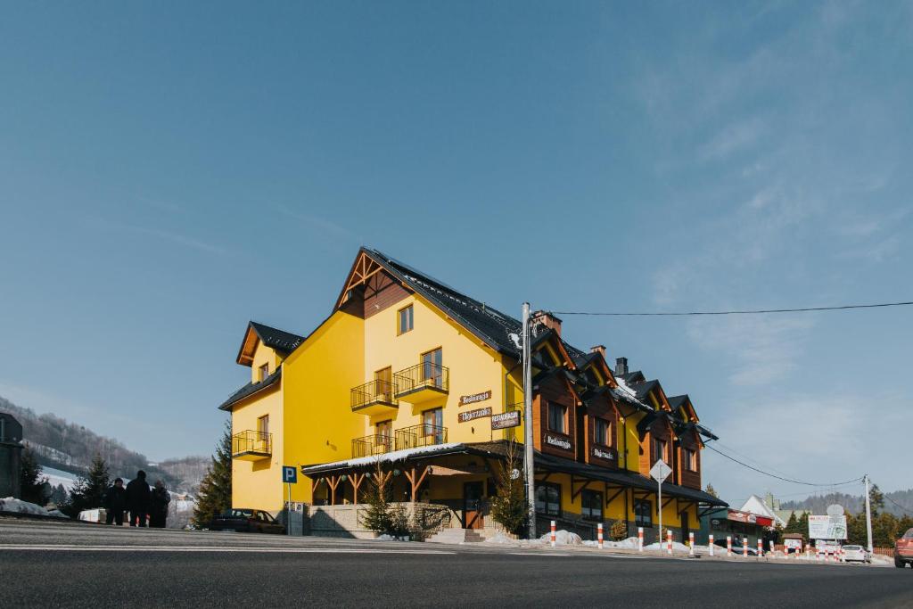 żółty budynek po stronie ulicy w obiekcie Hotel Majerzanka w mieście Piwniczna