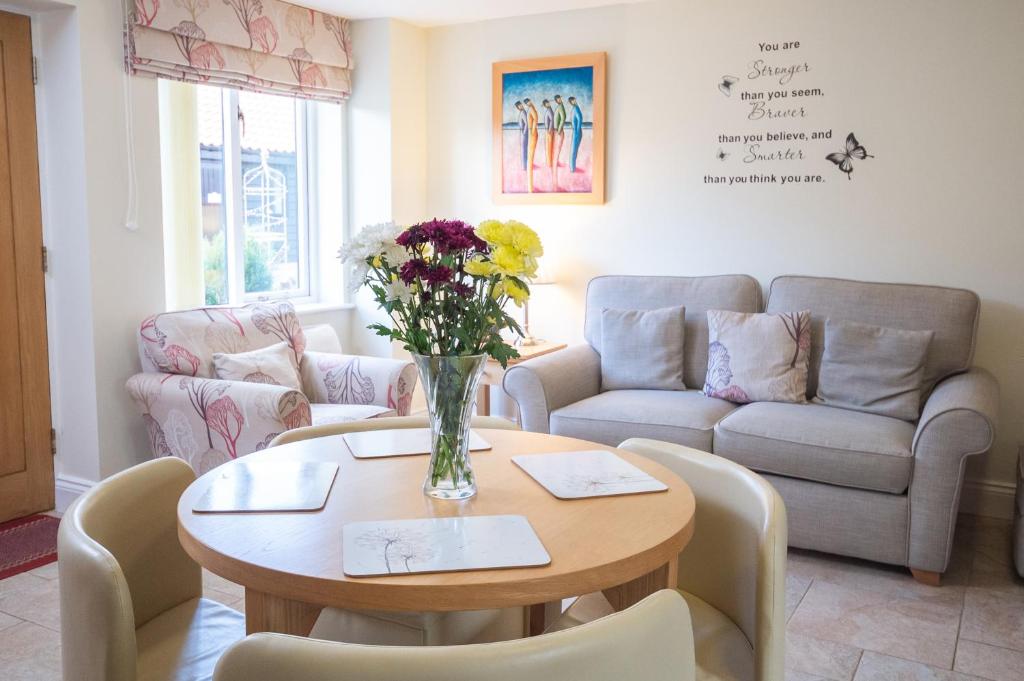 uma sala de estar com uma mesa com um vaso de flores em Mollett's Farm em Saxmundham