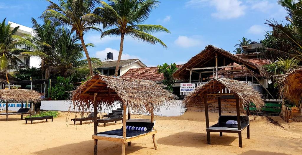 希卡杜瓦的住宿－海洋之光賓館，海滩上的一组椅子和遮阳伞