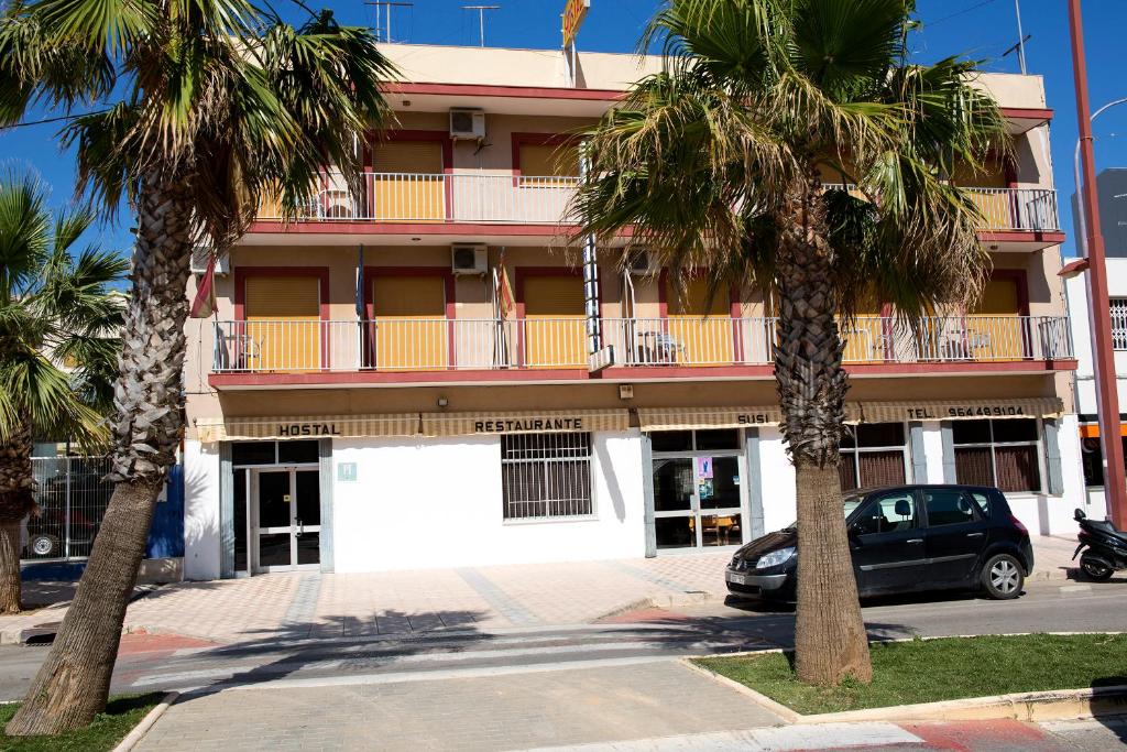 a car parked in front of a building with palm trees at Hostal Susi in Peniscola