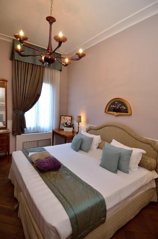 une chambre avec un grand lit blanc avec un lustre dans l'établissement B&B Villa Ines, sur le Lido de Venise