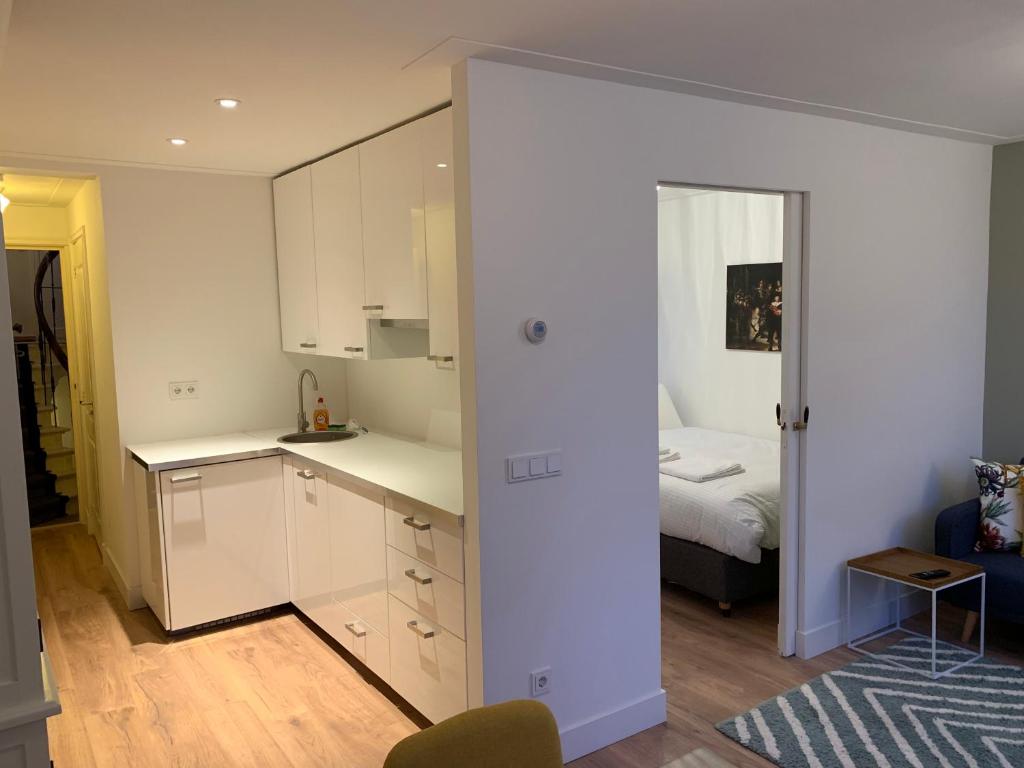 eine Küche mit weißen Schränken und ein Bett in einem Zimmer in der Unterkunft Kangaroom in Amsterdam