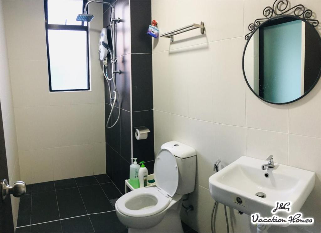 uma casa de banho com um WC, um lavatório e um espelho. em City Life by J&G Vacation Homes em Skudai
