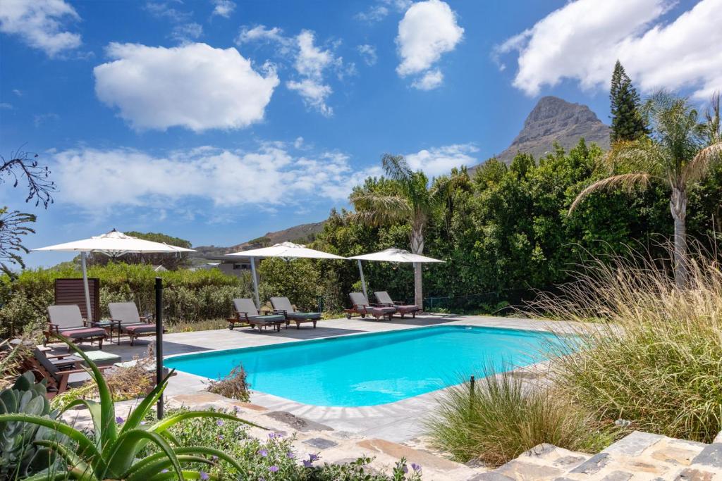 a pool with chairs and umbrellas and a mountain at Sovn Experience+Lifestyle in Cape Town