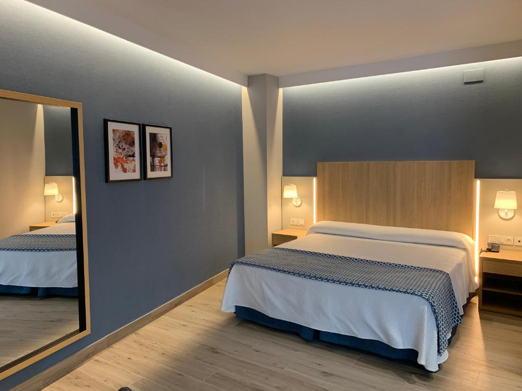 a bedroom with a large bed and a mirror at Hotel Puerta del Mar - Adults Recommended in Nerja