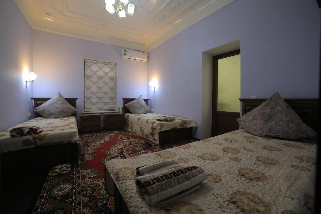 a hotel room with two beds and a window at Alliance hotel bukhara in Bukhara