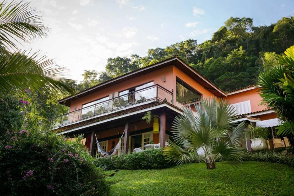 a pink house with a balcony in a garden at Pousada Pedras Brancas in Niterói