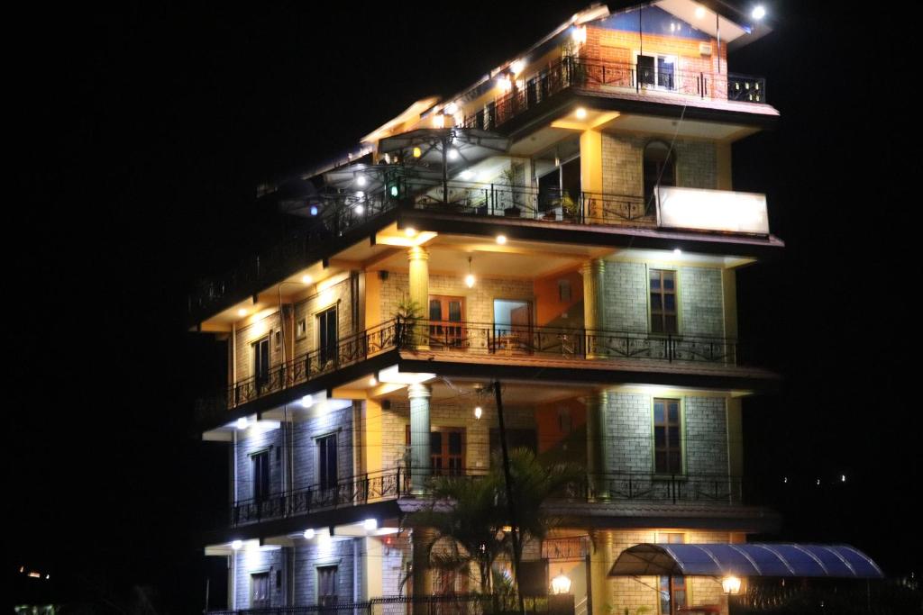 a tall building with balconies at night at Hotel Young's Stupa in Rānīpauwa