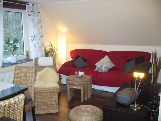 ein Wohnzimmer mit einem roten Sofa und einem Tisch in der Unterkunft Voßhörn 27, Ferienwohnung 4 in Cuxhaven