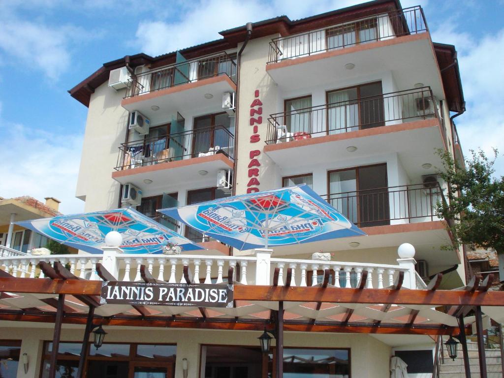 a tall building with umbrellas in front of it at Guest House Ianis Paradise in Nesebar