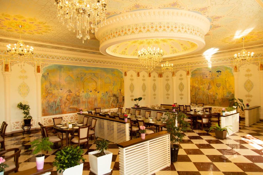 Cinzano Complex في سمرقند: مطعم بطاولات وكراسي في غرفة بها لوحات