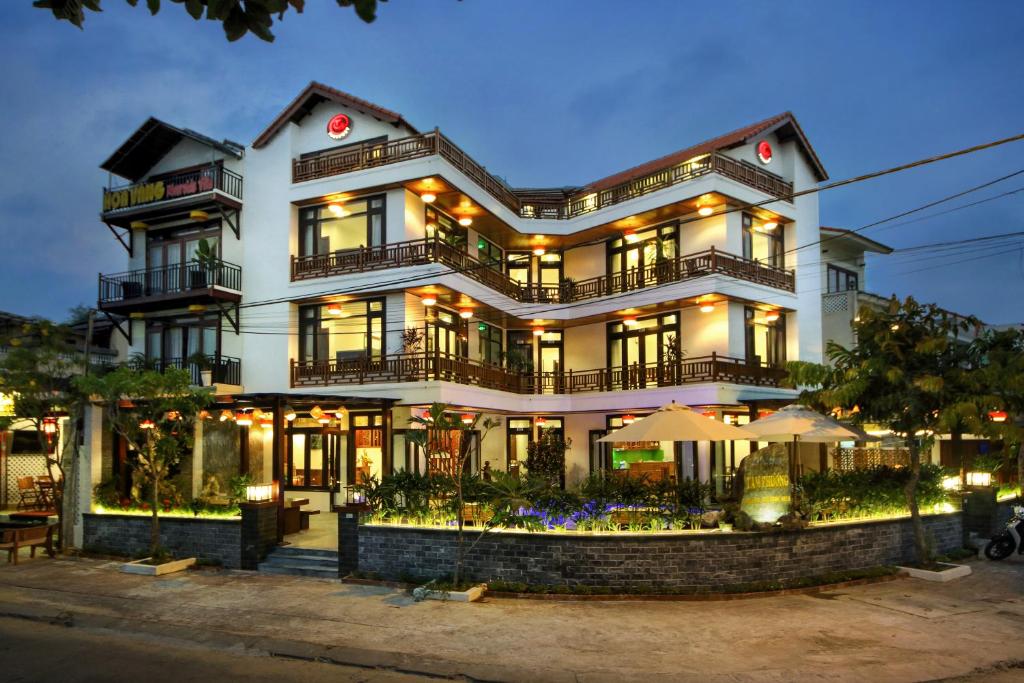 een groot wit gebouw met verlichting aan bij Threeway Riverside Villa in Hội An