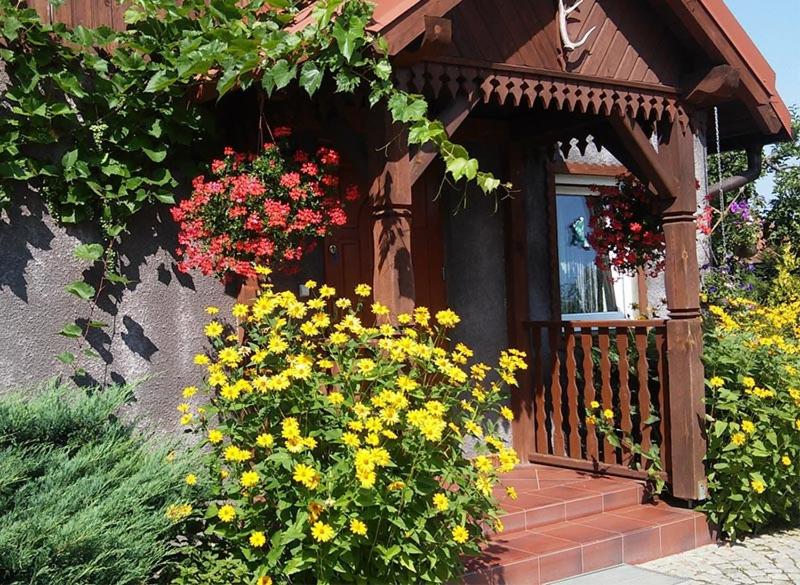 un porche con flores frente a una casa en Gościniec Gałkowo, en Gałkowo