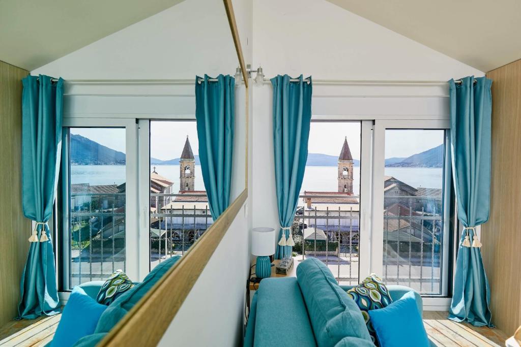 sala de estar con muebles azules y ventanas grandes. en Bayview Studio Apartment en Tivat