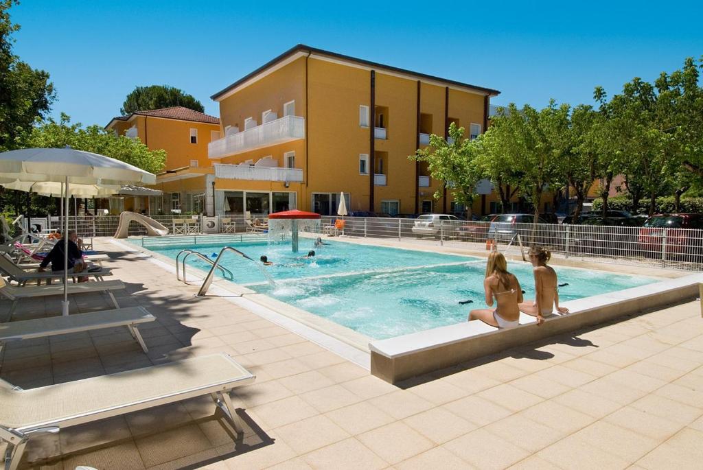 dos chicas sentadas en una piscina en un hotel en Hotel Giuliana, en Cervia