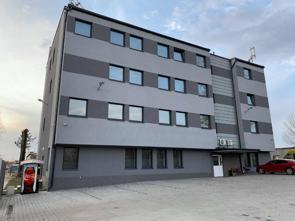 a large white building with a red car in front of it at Noclegi Europol in Siemianowice Śląskie