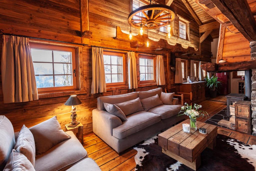 a living room with couches and a table and windows at Chez « Adèle » in Ayent