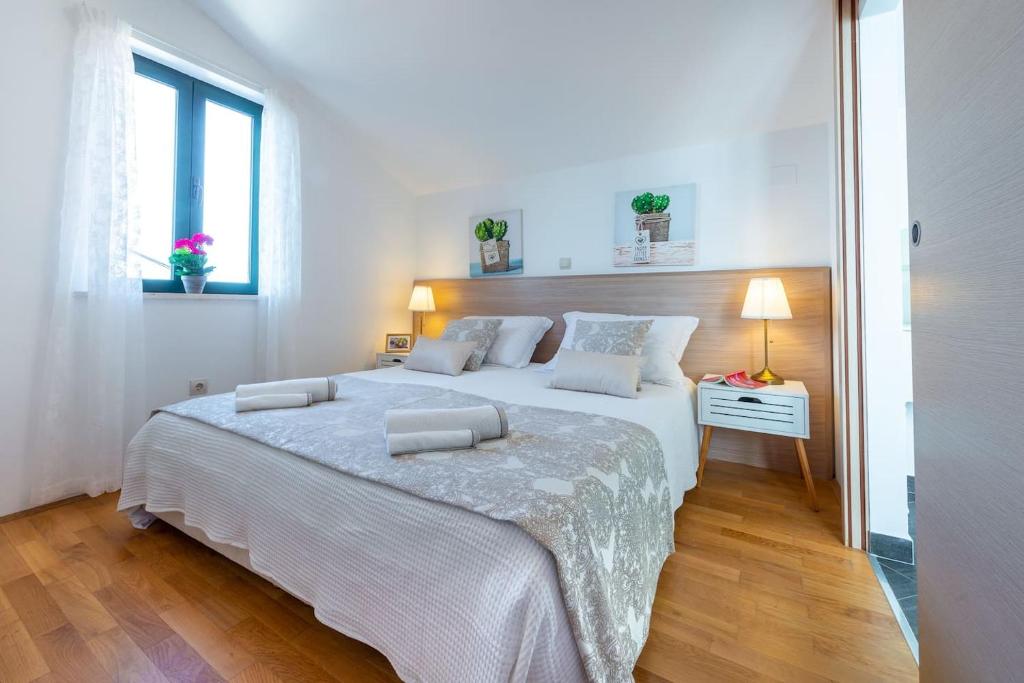 a white bedroom with a large bed and a window at Mariposa in Dubrovnik