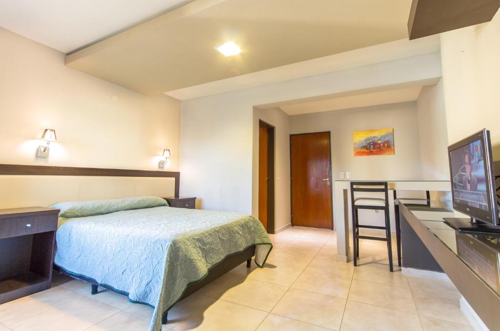 um quarto com uma cama, uma secretária e uma televisão em Casa Decla em Villa Carlos Paz