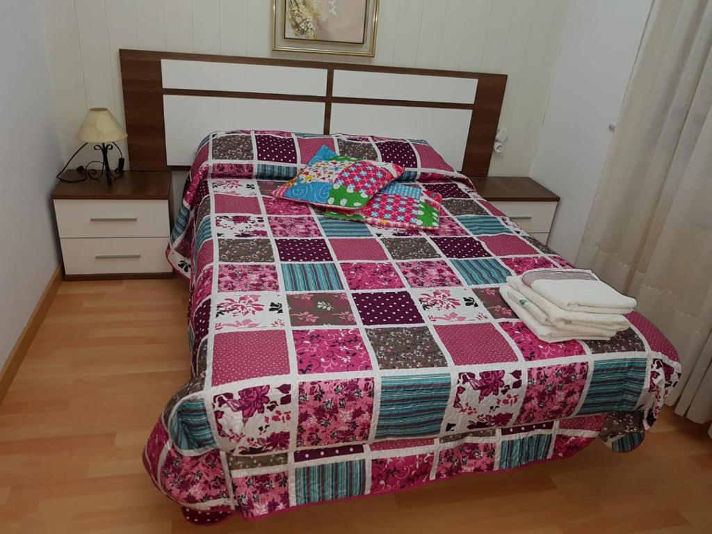 a bedroom with a bed with a quilt on it at HOSTAL BODEGÓN A COSECHA in San Ciprián