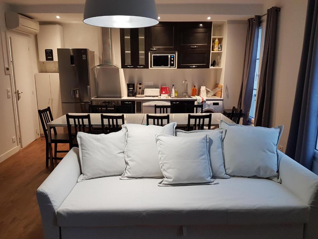 ein Wohnzimmer mit einem weißen Sofa und einer Küche in der Unterkunft Meublés de Tourisme à Vincennes in Vincennes