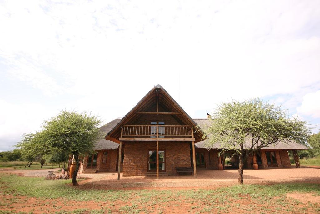 una casa con techo de paja y 2 árboles en Makhato Bush Lodge 109, en Bela-Bela