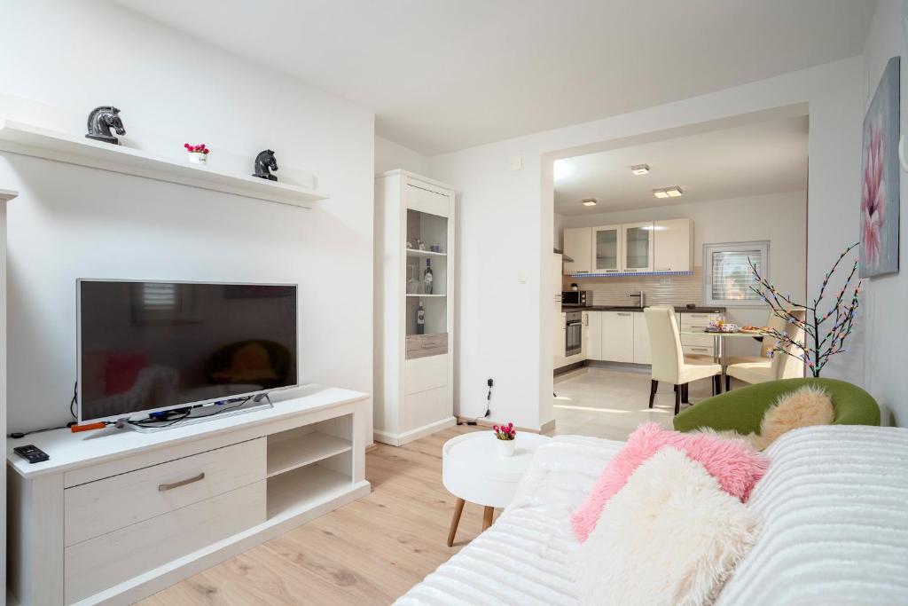 ein Wohnzimmer mit einem weißen Sofa und einem TV in der Unterkunft Antonella in Vrboska