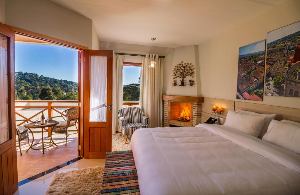 a bedroom with a bed and a balcony with a fireplace at Pousada Suiça Mineira Centro in Monte Verde