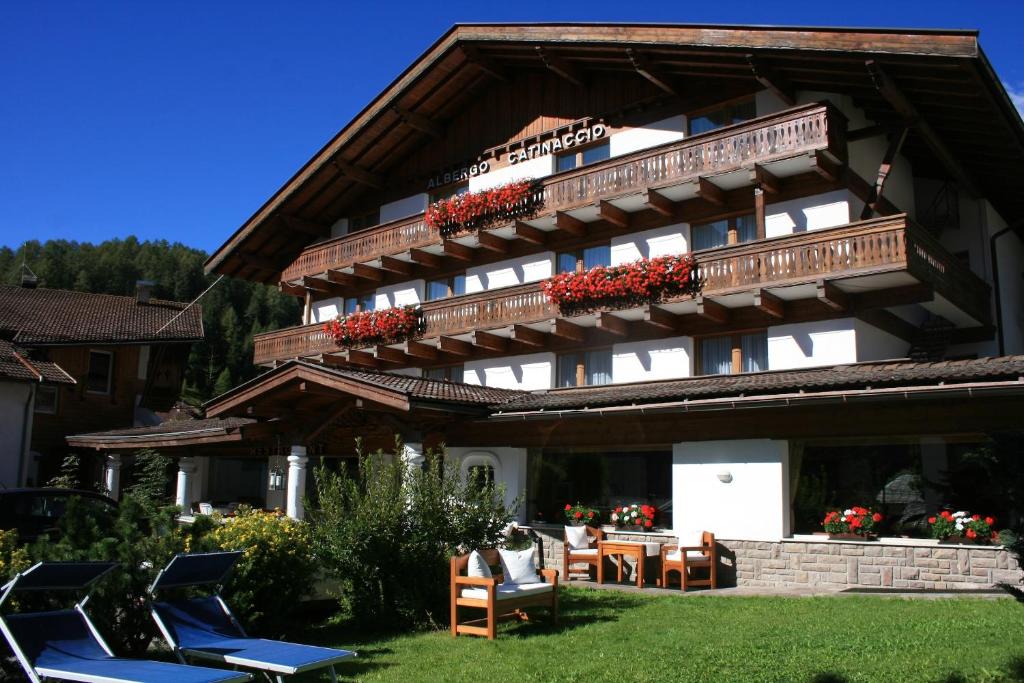 ein großes Gebäude mit Stühlen und Tischen im Hof in der Unterkunft Hotel Catinaccio in Vigo di Fassa