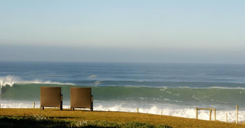 two benches sitting on the beach near the ocean at 4Sea House in Porto Covo