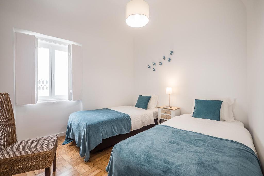 a room with two beds and a chair and a window at Casa dos Mouros in Évora