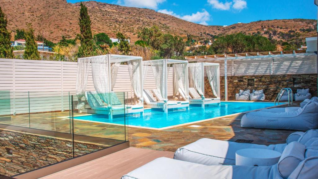 a swimming pool with white chairs and a swimming pool at Andros Luxury House in Kipri