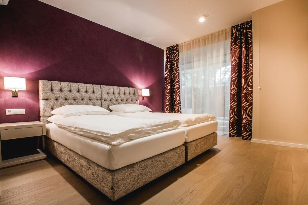 1 dormitorio con 1 cama grande y pared morada en Karl Suites Palais Wessely, en Viena