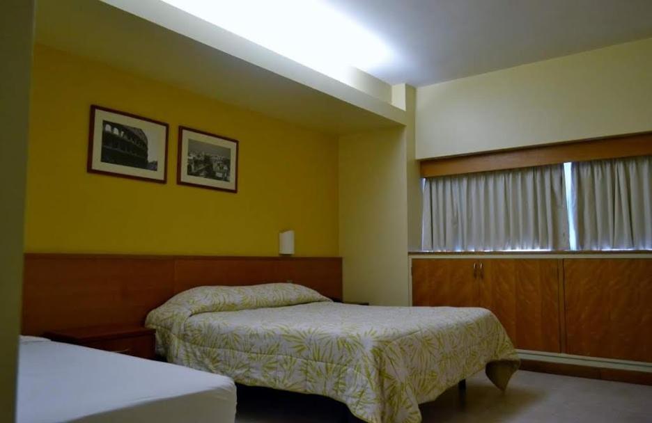 a hotel room with two beds and a window at Hotel Coliseo in Caracas