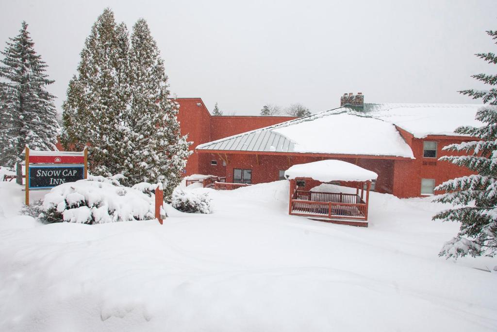 un bâtiment recouvert de neige avec un panneau et des arbres dans l'établissement Snow Cap Inn, à Newry
