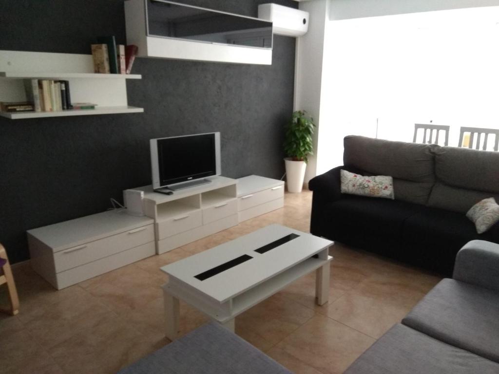 a living room with a couch and a tv at Piso Almería playa in Almería