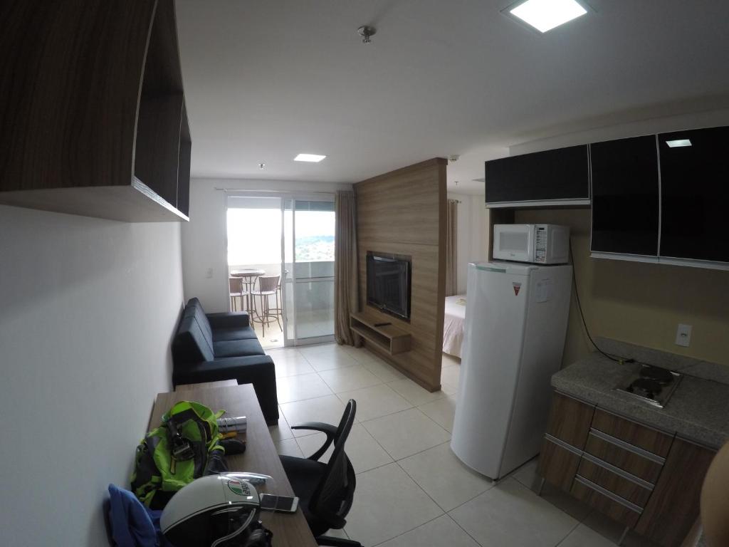 uma cozinha com um frigorífico branco e uma sala de estar em Flat no Brookfield Towers em Goiânia